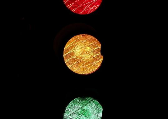 image shows red, yellow and green traffic lights on a black background.