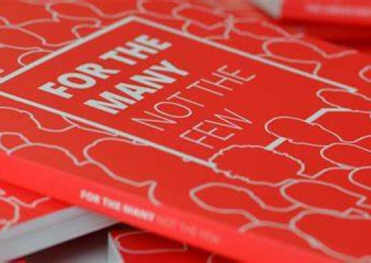 image shows copies of labour manifesto 2024. The book cover is red with the words, written in white : For the many, not the few.